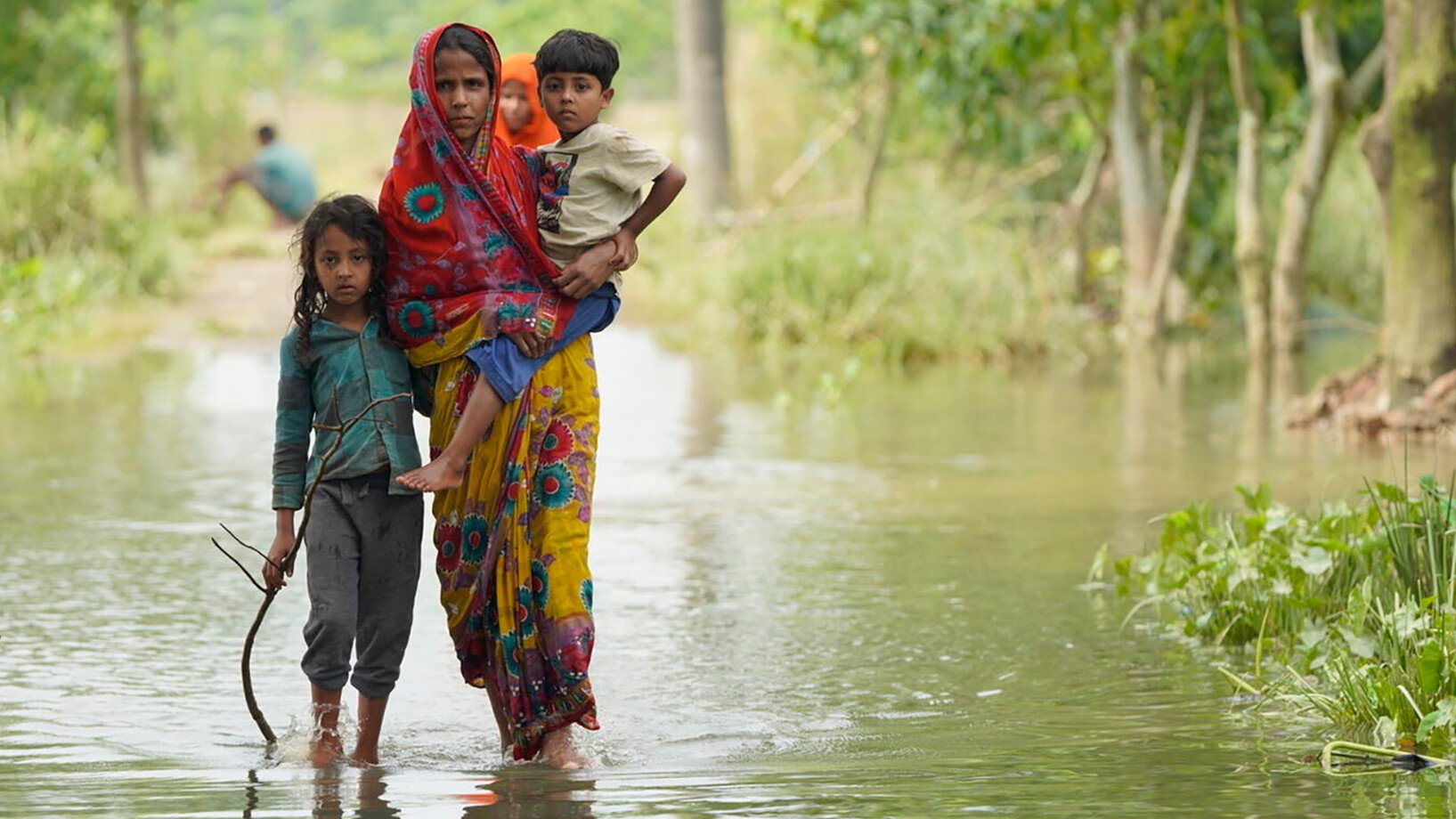 Eine Mutter steht mit ihrer Tochter und ihrem Sohn in Sylhet im Wasser, als der Nordosten Bangladeschs von heftigen Überschwemmungen heimgesucht wird.