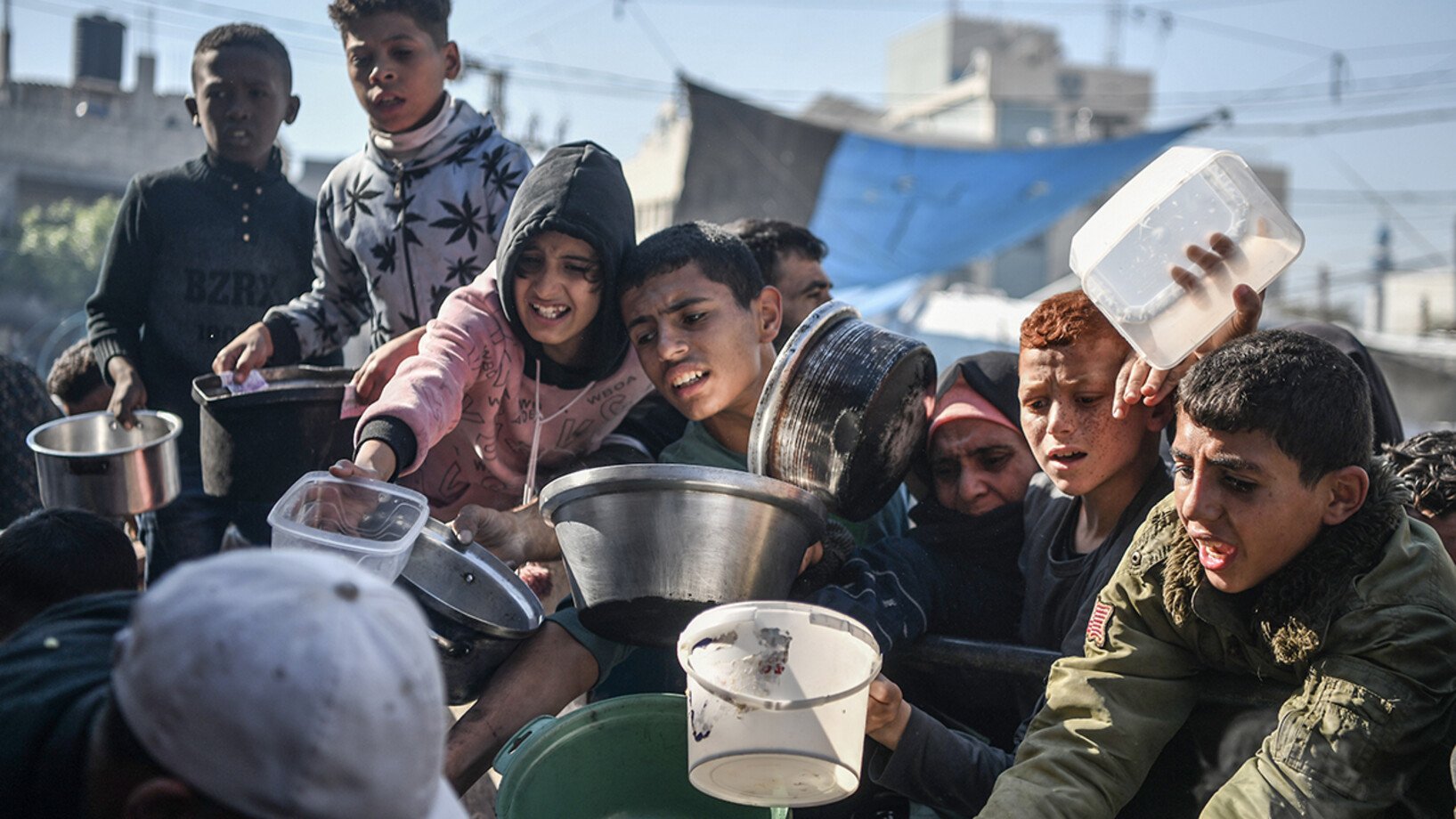 Kinder warten in der Stadt Rafah im südlichen Gazastreifen in einer langen Schlange, um eine kleine Menge an Lebensmitteln zu erhalten.