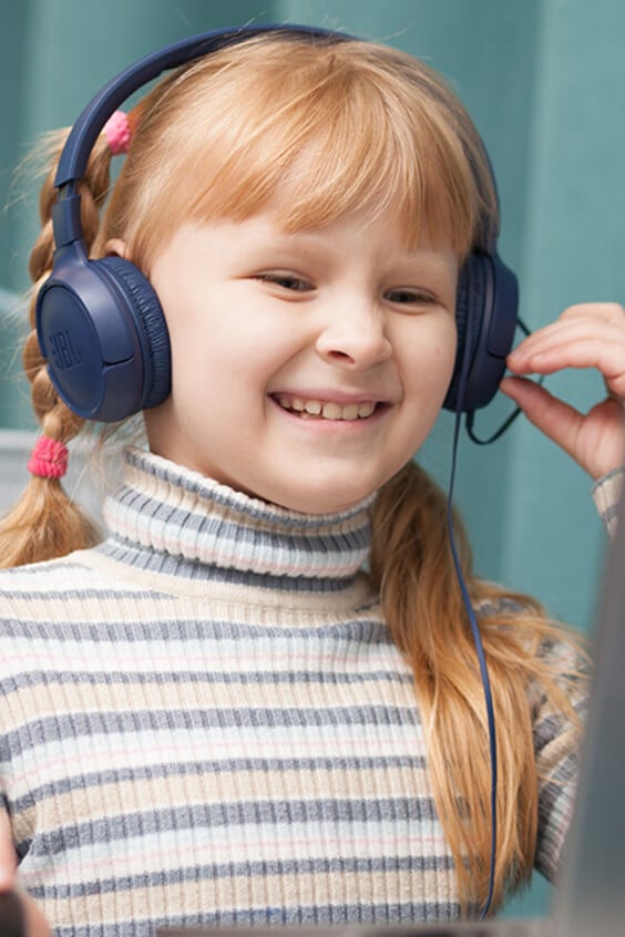 Ein Kind sitzt mit Kopfhörern vor einem Computer.