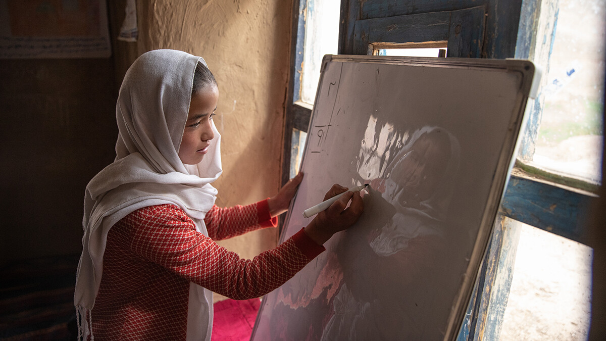 Ein afghanisches Mädchen schreibt während einer Mathematikstunde an die Tafel.
