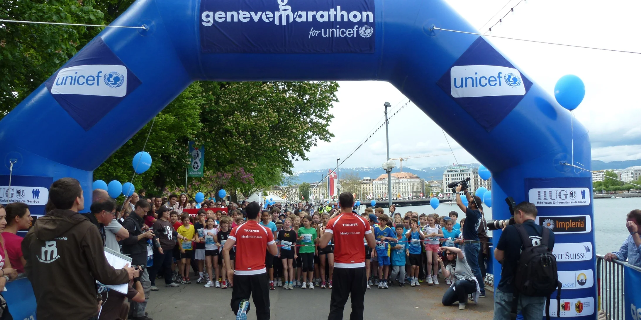Départ de la course des enfants. Enfants prêts à courir et portail muni de divers logos.