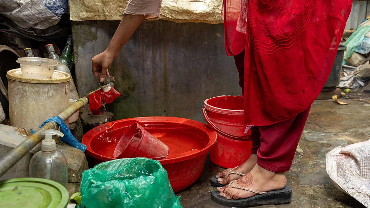Eine Frau befüllt ihre Kochtöpfe mit sauberem Trinkwasser.