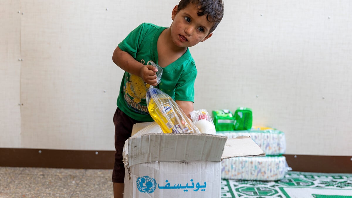Ein kleiner Junge packt eine UNICEF-Hilfspaket aus.