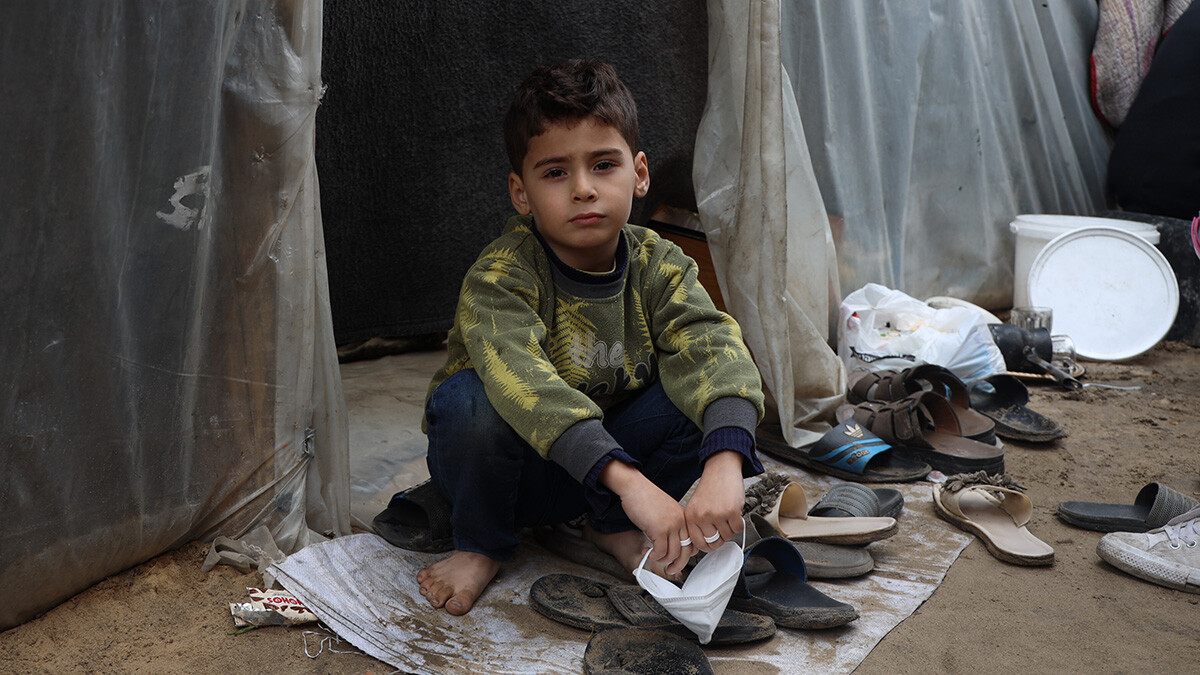 Ein Junge sitzt in Gaza in vor einem provisorisch aufgestellten Zelt.