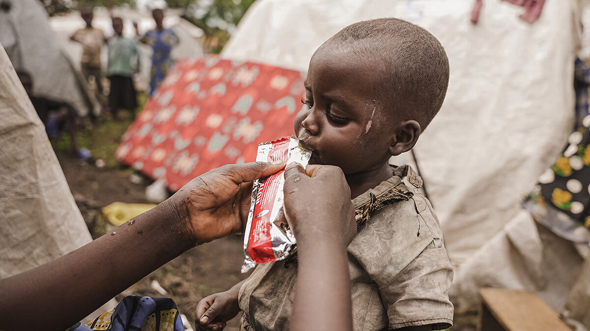 Ein kleines Mädchen isst eine Packung mit gebrauchsfertiger therapeutischer Nahrung vor ihrer Unterkunft.