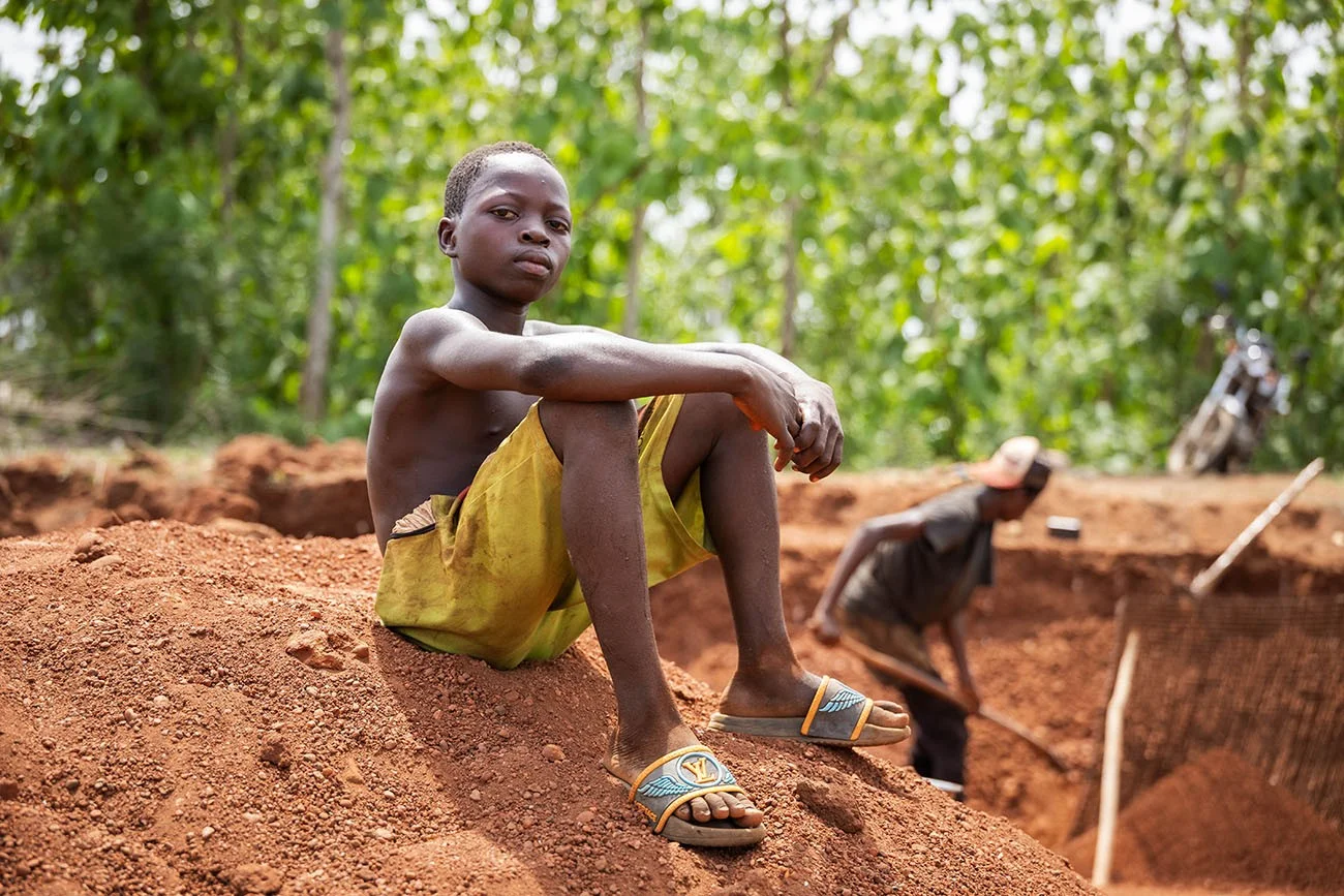 Le 12 mars 2025, Jean [NOM MODIFIÉ], âgé de 12 ans, est assis au sommet d'un tas de sable dans la carrière de gravier où il travaille à Couffo, au Bénin.