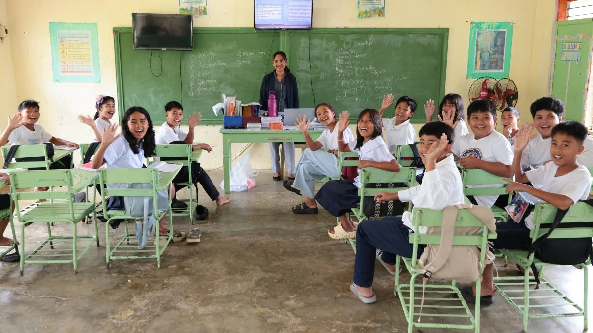 Gli alunni sono seduti in classe e salutano con la mano