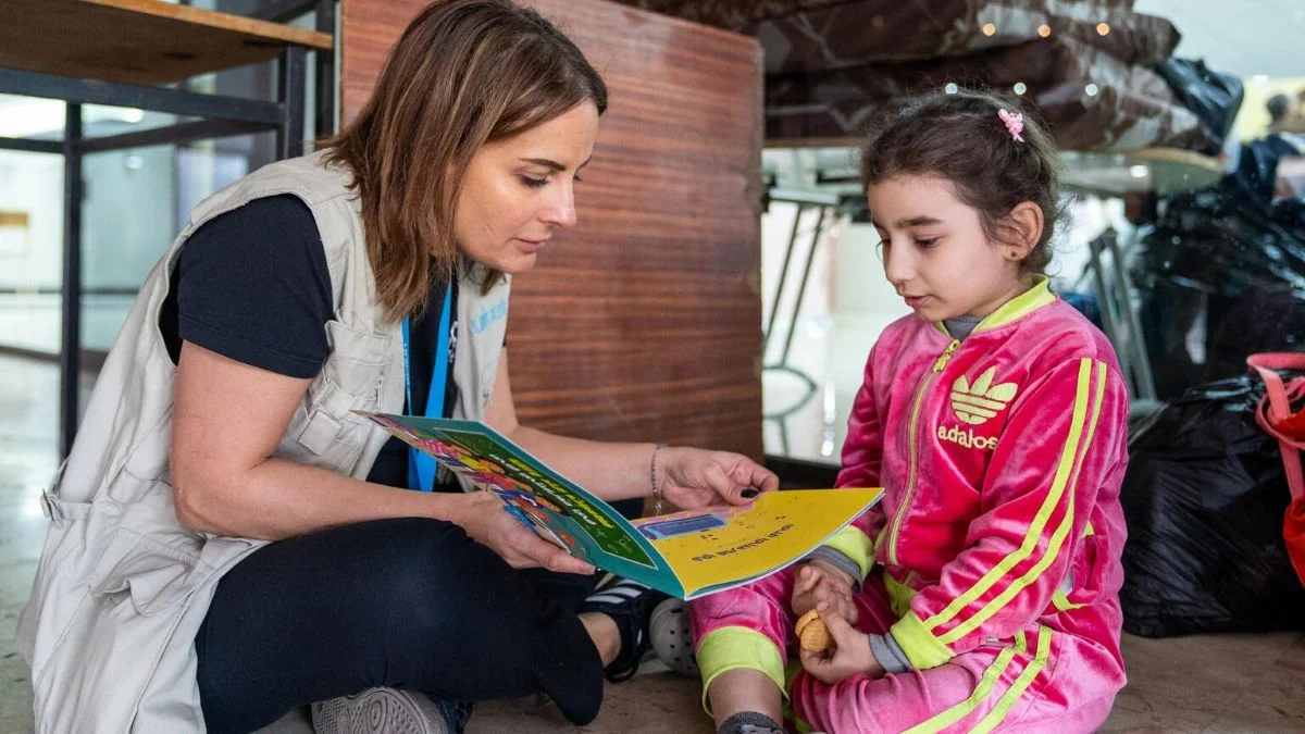Eine UNICEF Mitarbeiterin liest einem Mädchen vor