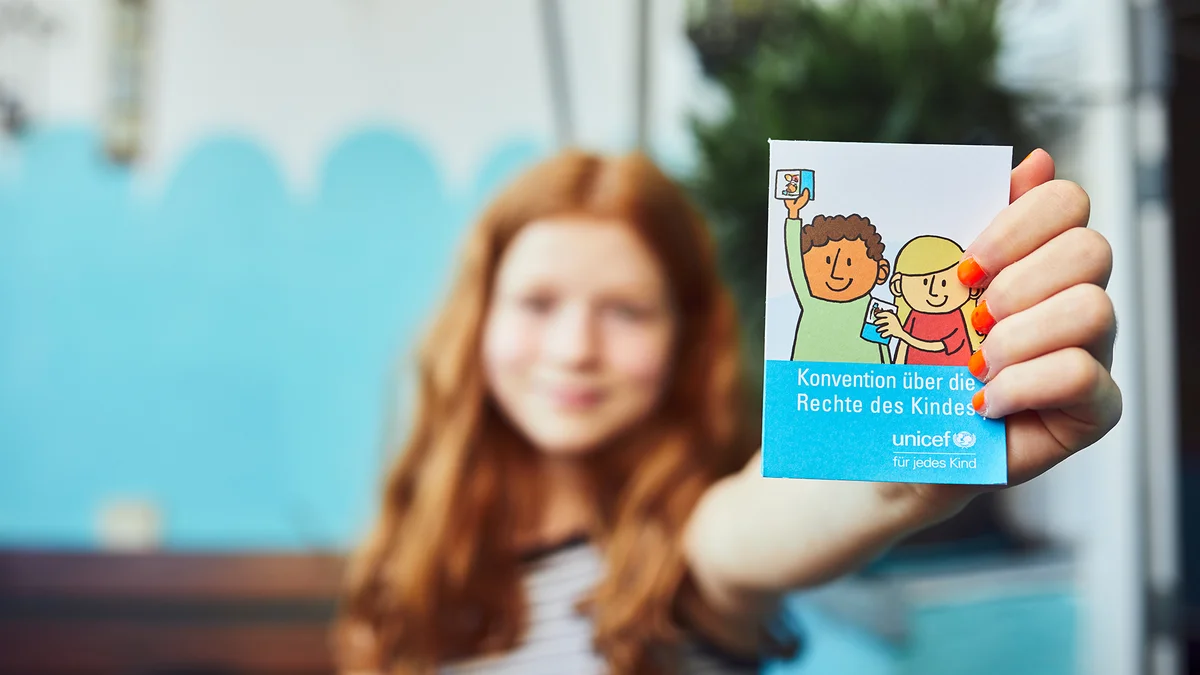 Mädchen hält das Deutsche Grundgesetz in die Kamera.