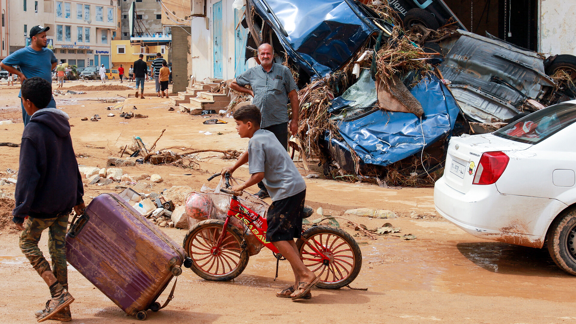 Ein Junge zieht am 11. September 2023 in einem von Sturzfluten zerstörten Gebiet in Derna, Ostlibyen, einen Koffer an Trümmern vorbei. 