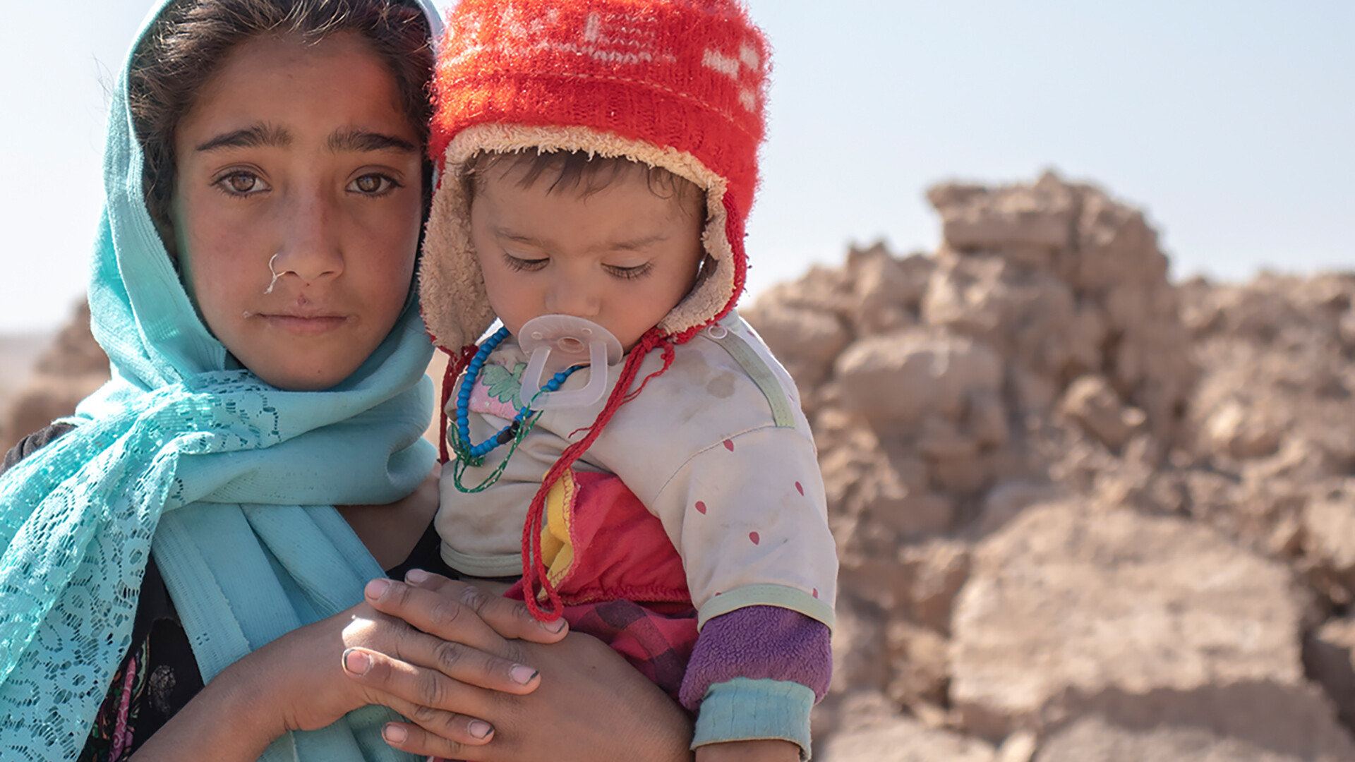 Afghanisches Mädchen hält ihren Bruder nach dem Erdbeben im Arm.