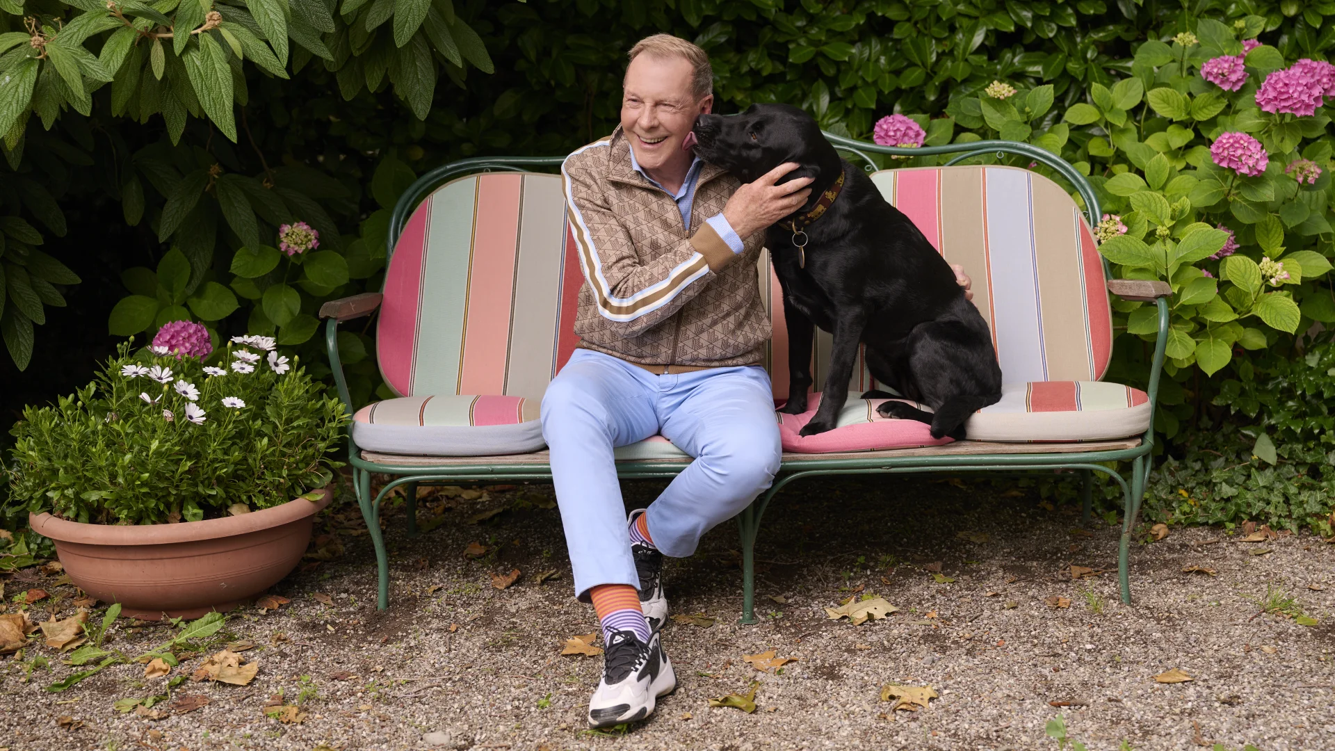 Kurt Aeschbacher mit seinem Hund auf einer Bank in seinem Garten.