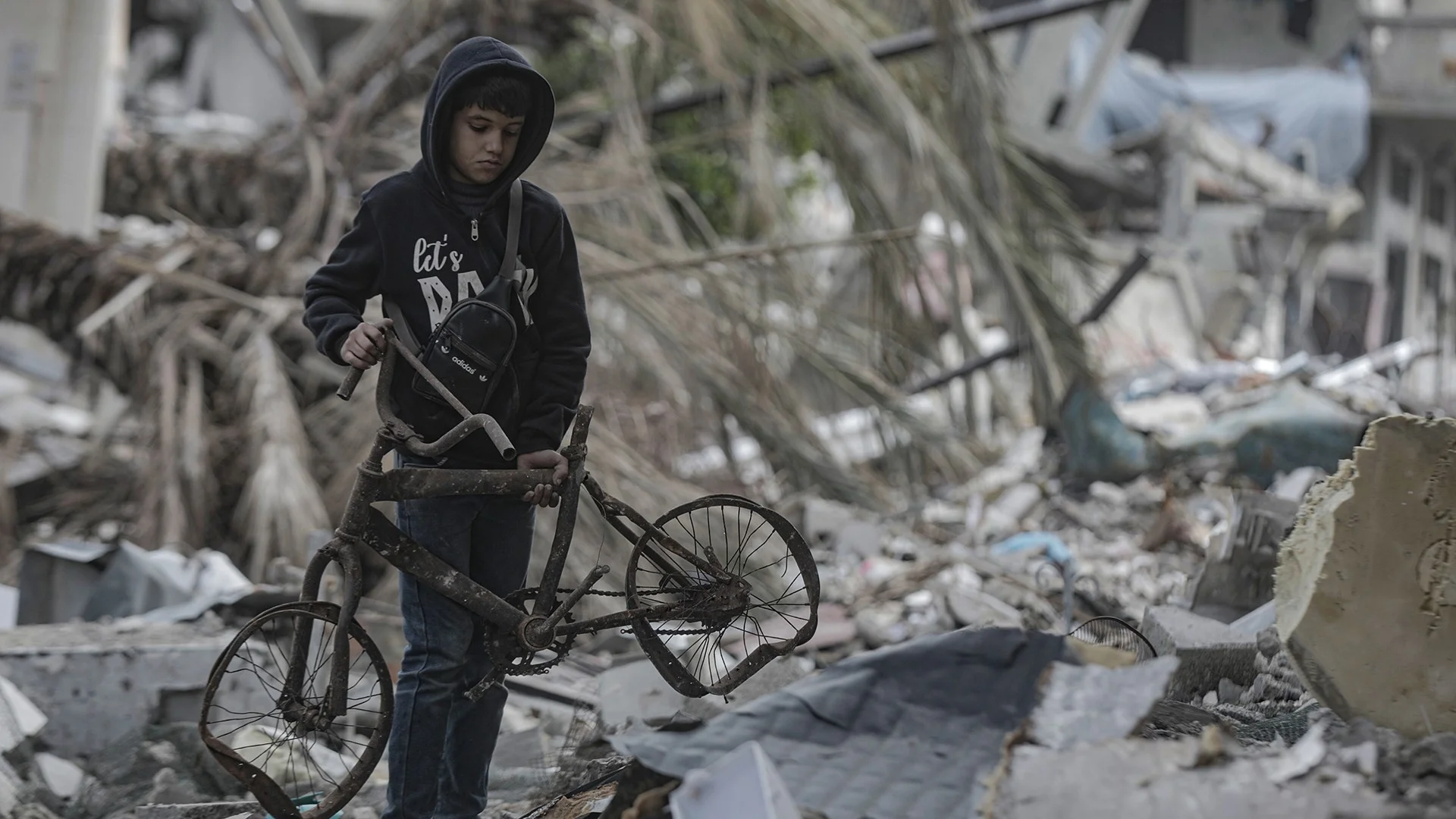 Bub mit zerstörtem Velo in Trümmern im Gazastreifen