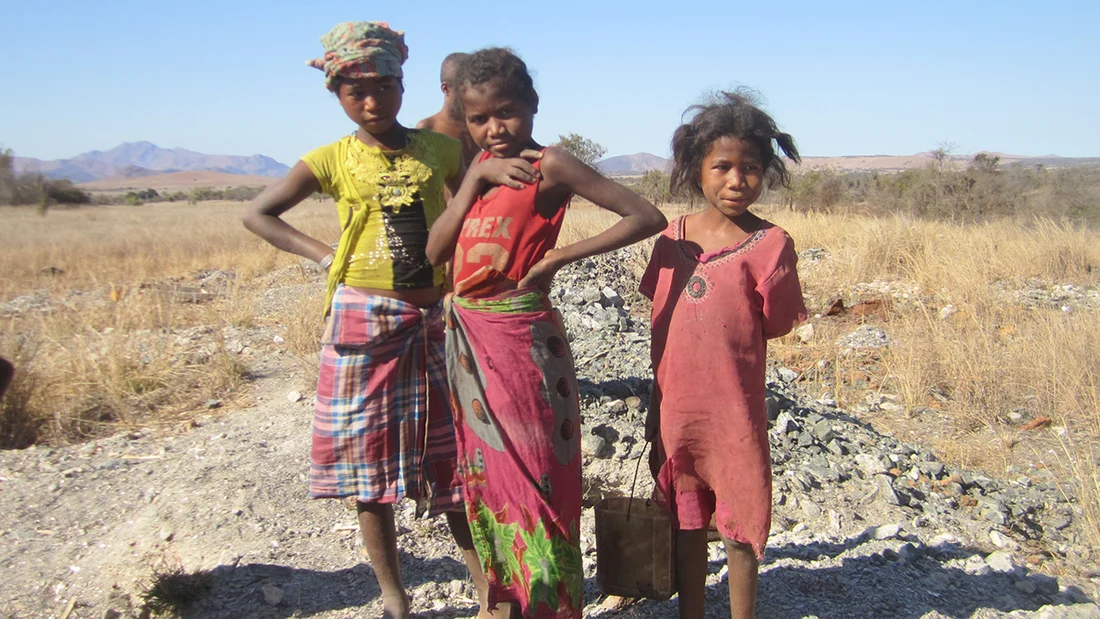 Tre bambini sono in piedi in un campo.