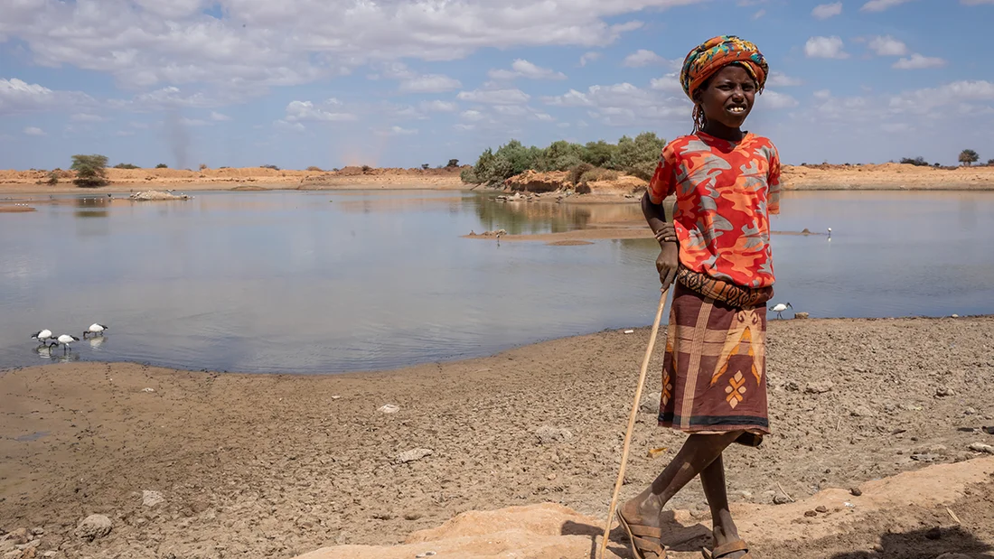 Un enfant se tient devant un point d'eau.