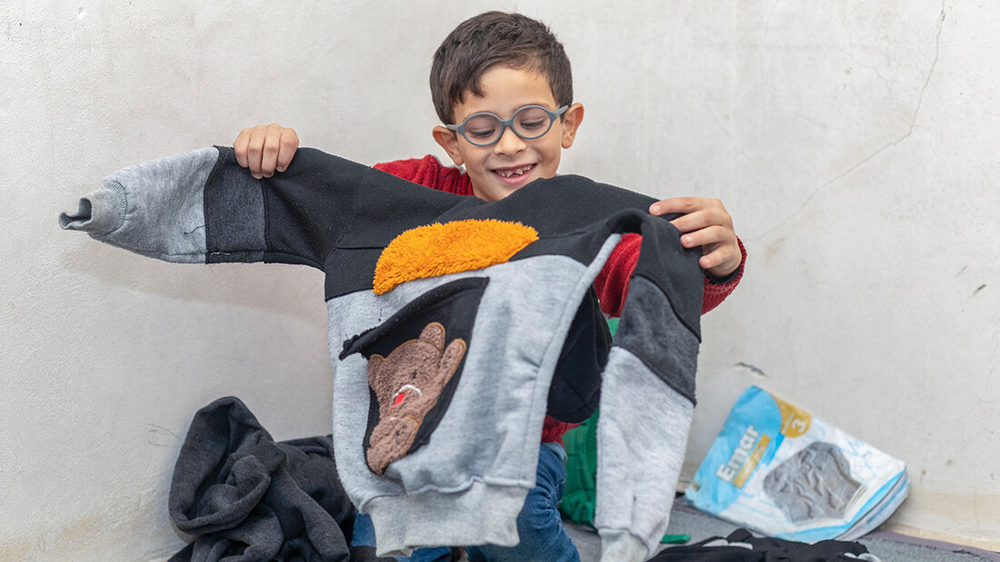 Radwan, 9 ans. tient son nouveau pull d’hiver que sa mère a pu acheter avec l’aide en espèces de l’UNICEF.