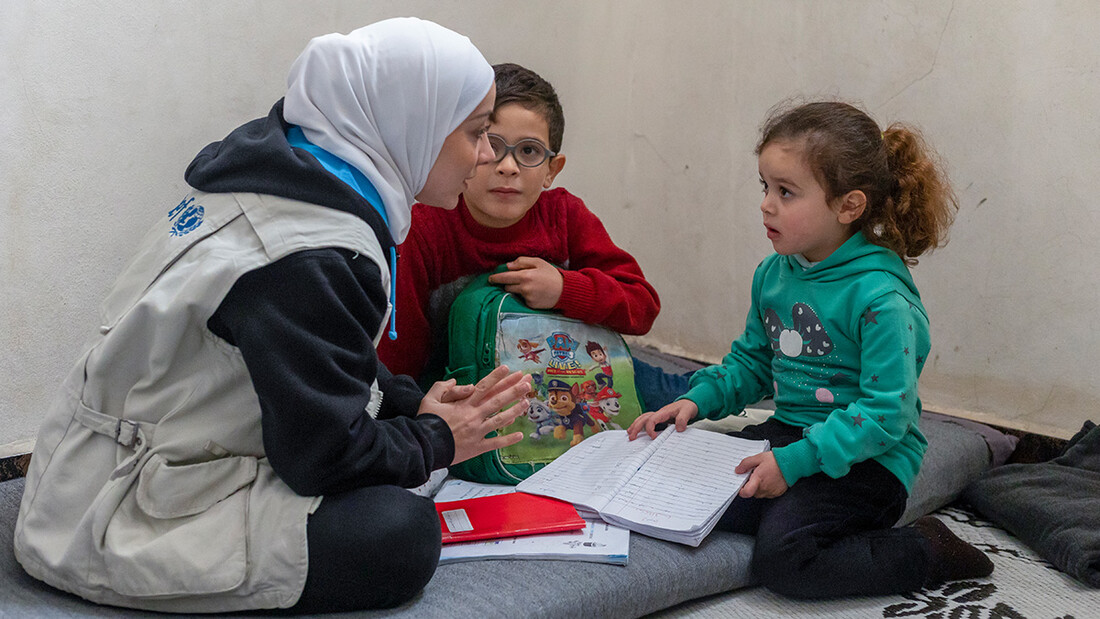 Yasmin Hulou, a UNICEF staff member, chatting with Radwan (9) and his sister Rimas (5) during a visit to their home in Aleppo. 