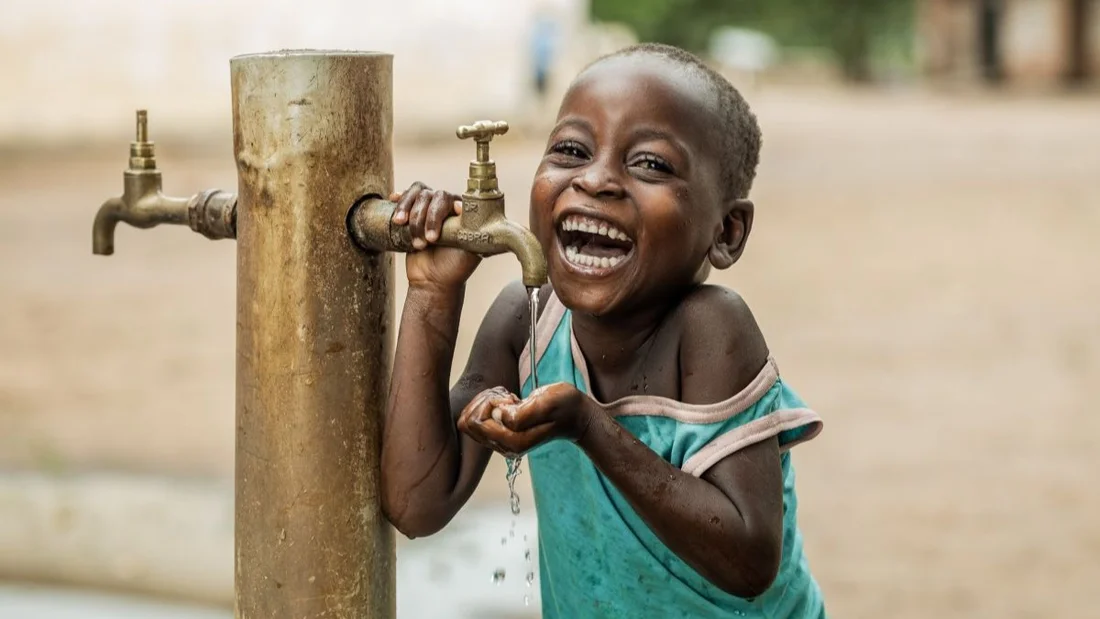 Un bambino del Malawi beve acqua.