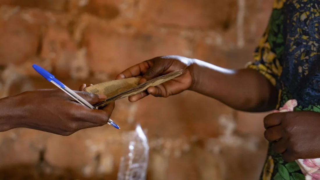 Una madre della Repubblica Democratica del Congo riceve fondi tramite un programma di trasferimento di denaro mobile per acquistare generi alimentari e avviare una piccola attività di orticoltura.