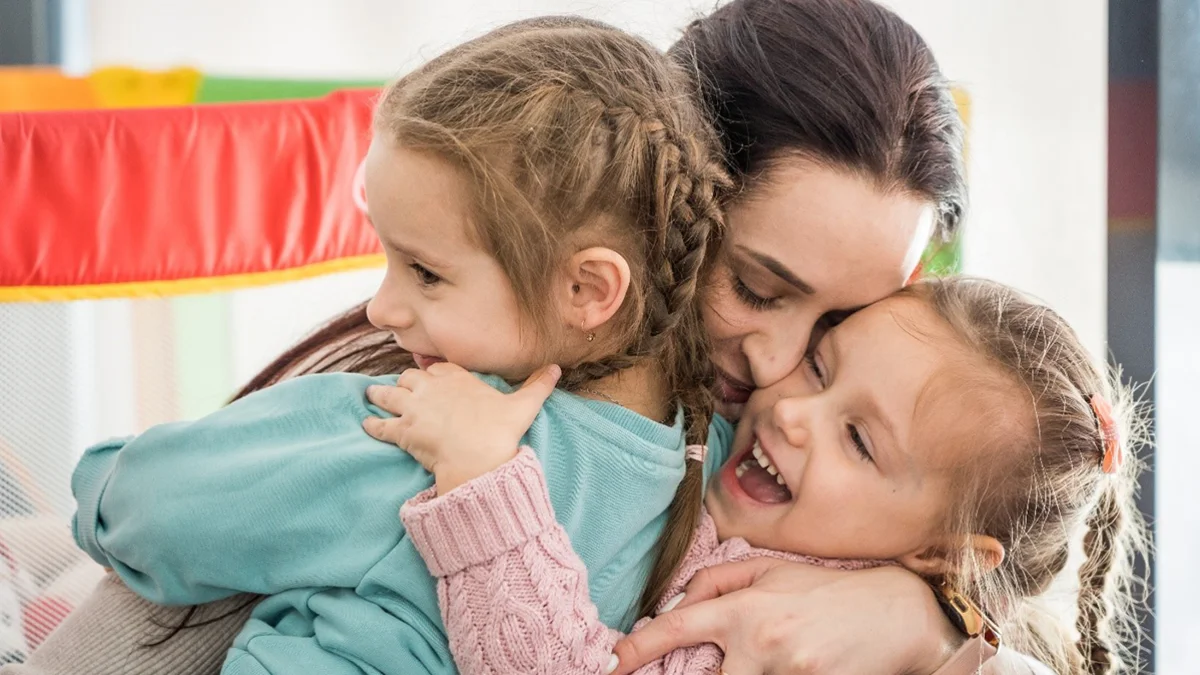 Mutter hält Kinder im Arm.