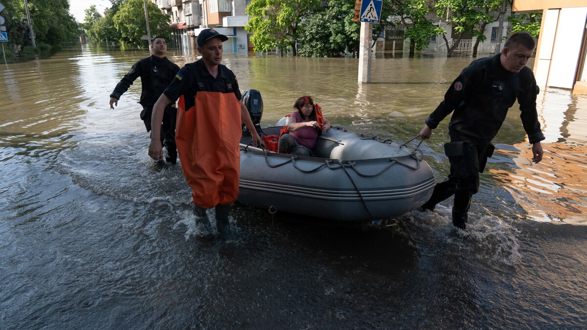 Ukrainische Sicherheitskräfte transportieren einen Anwohner in einem Boot während einer Evakuierung aus einem überschwemmten Gebiet in Kherson am 7. Juni 2023, nachdem der Damm des Wasserkraftwerks Kakhovka beschädigt wurde.