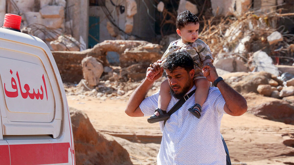 Ein Vater trägt sein Kind durch die zerstörten Strassen von Derna.