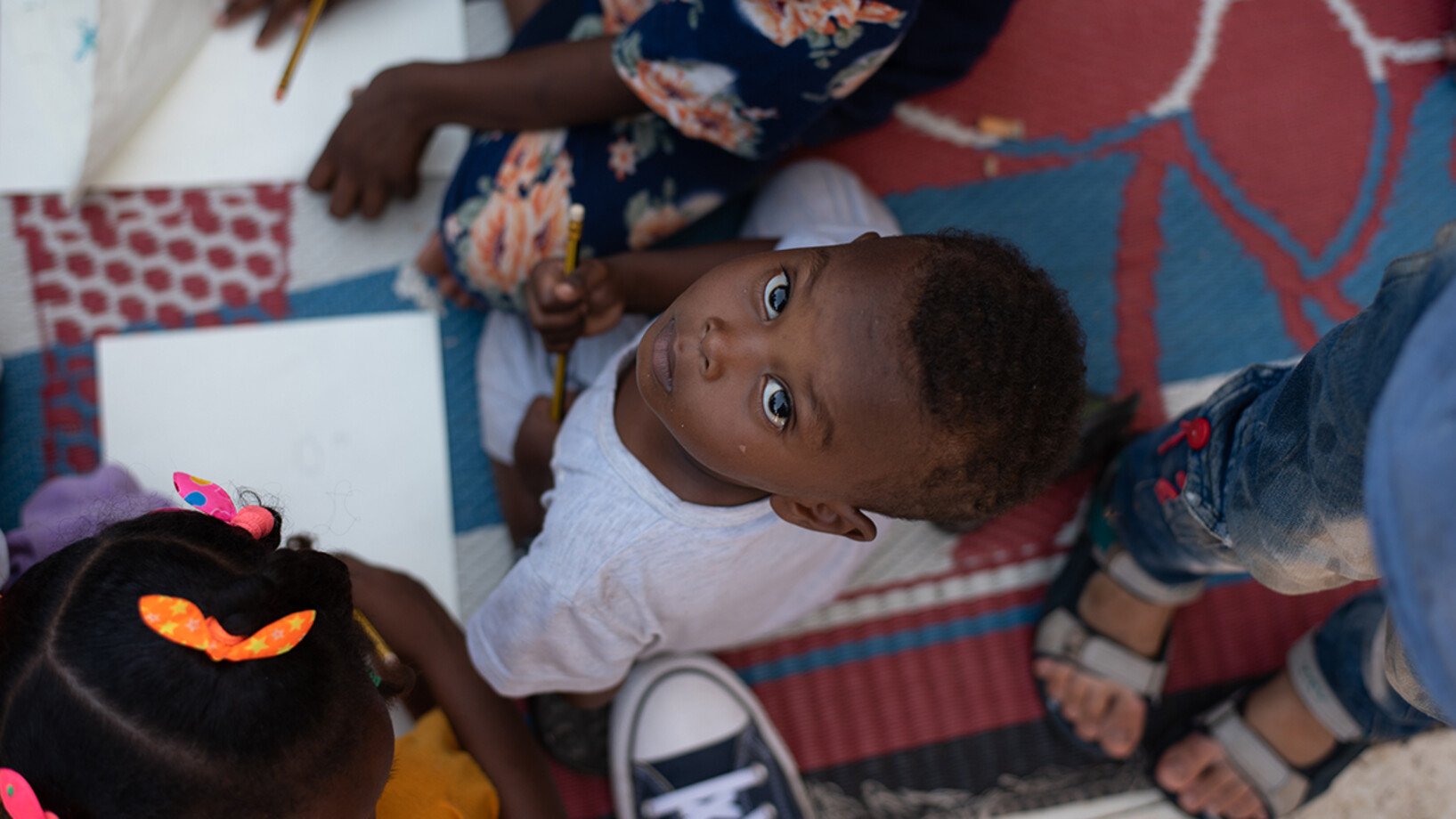 Sudanesischer Junge sitzt in einer Notunterkunft und malt.