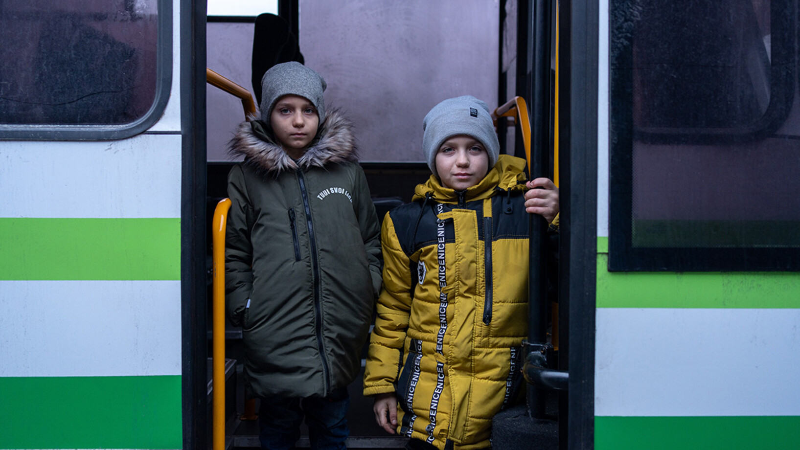 Zwei Jungen stehen vor einem Bus.