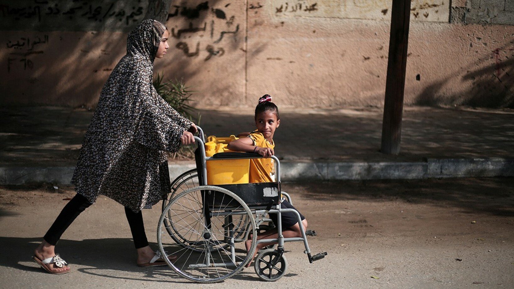 Gaza Maedchen transportieren Wasser im Rollstuhl