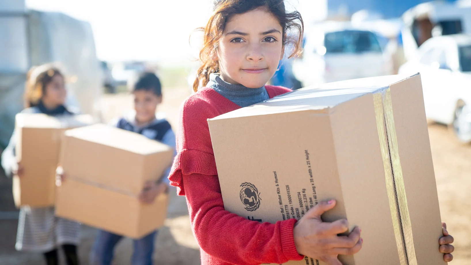 Mädchen trägt Hilfskarton von UNICEF