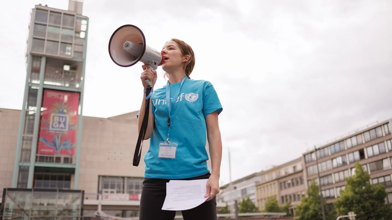 Mädchen trägt ein UNICEF T-Shirt und spricht in ein Megafon 