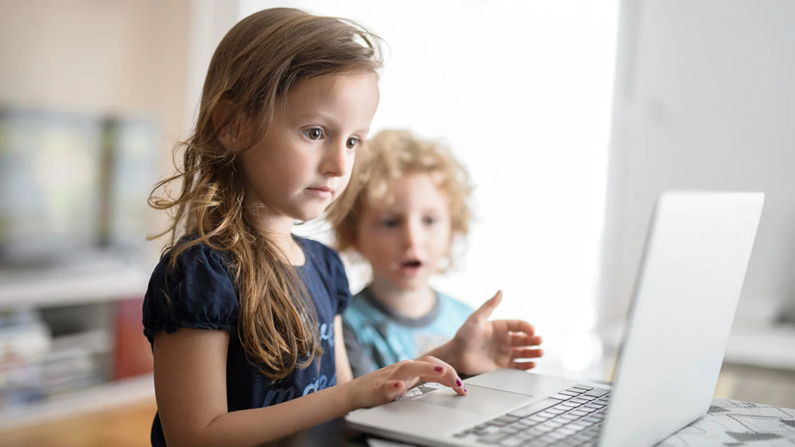 Ein Mädchen und ein Bub sitzen vor einem Laptop