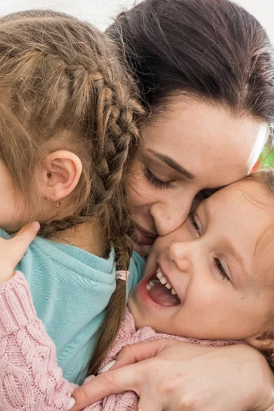 Mutter hält Kinder im Arm.
