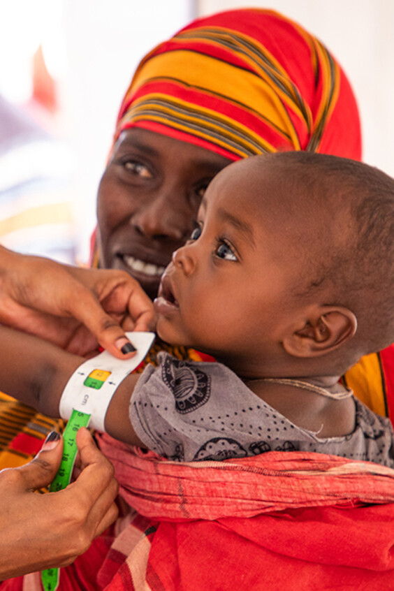 Un petit enfant reçoit un vaccin dans les bras de sa mère.