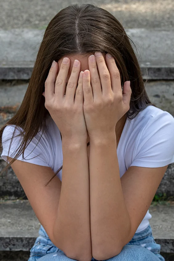 Jugendliches Mädchen schlägt Hände vors Gesicht