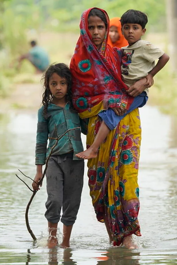 Eine Mutter steht mit ihrer Tochter und ihrem Sohn in Sylhet im Wasser, als der Nordosten Bangladeschs von heftigen Überschwemmungen heimgesucht wird.