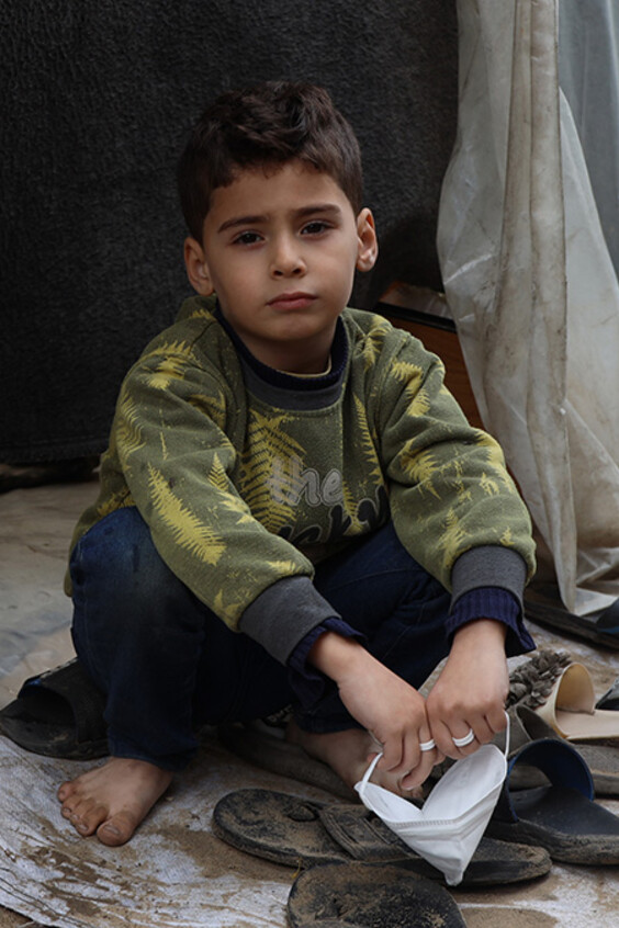 Ein Junge sitzt in Gaza in vor einem provisorisch aufgestellten Zelt.