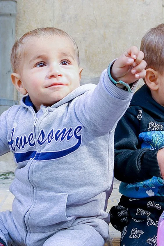 Zwei kleine Kinder sitzen auf dem Boden