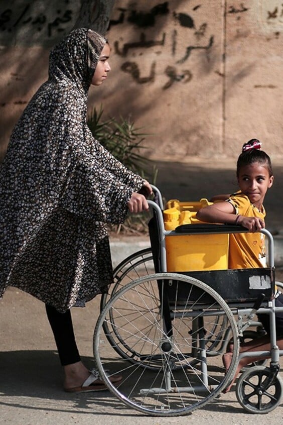 Gaza Maedchen transportieren Wasser im Rollstuhl