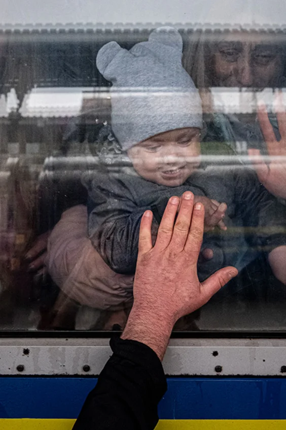 Ein Mann streckt seine Hand an die Scheibe eines Zuges, das Kind und seine Mutter in dem Zug drücken ihre Hand zum Abschied von Innen auf das Glas.
