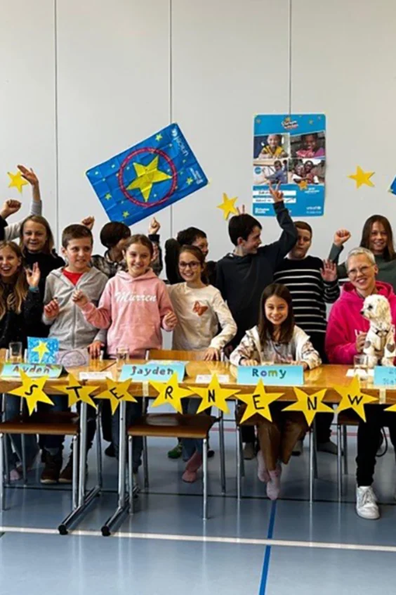 Viele Kinder und Stefanie Heinzmann lächeln in die Kamera.