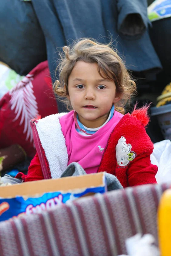 Zwei Kinder sitzen mit vielen Kisten und Sachen in einem Wagen.