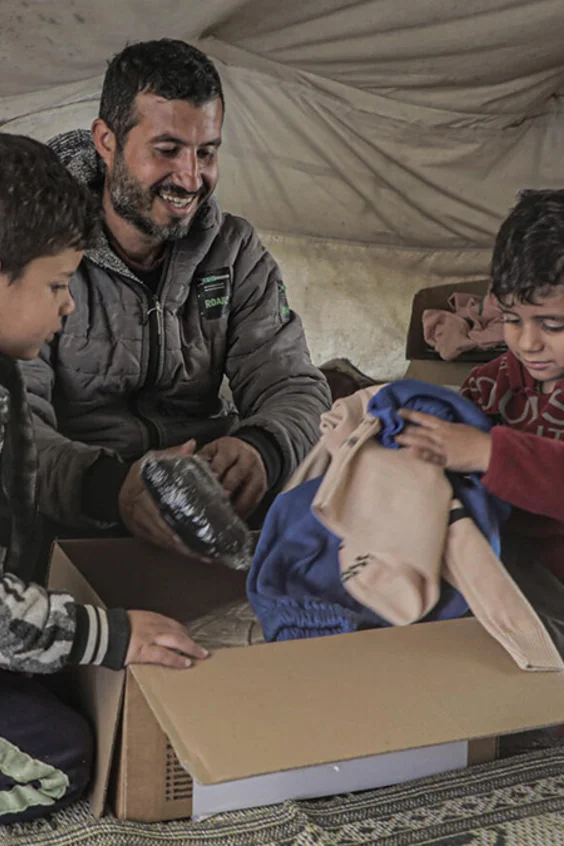 Eine Familie schaut gespannt in den Inhalt einer UNICEF-Hilfsbox.