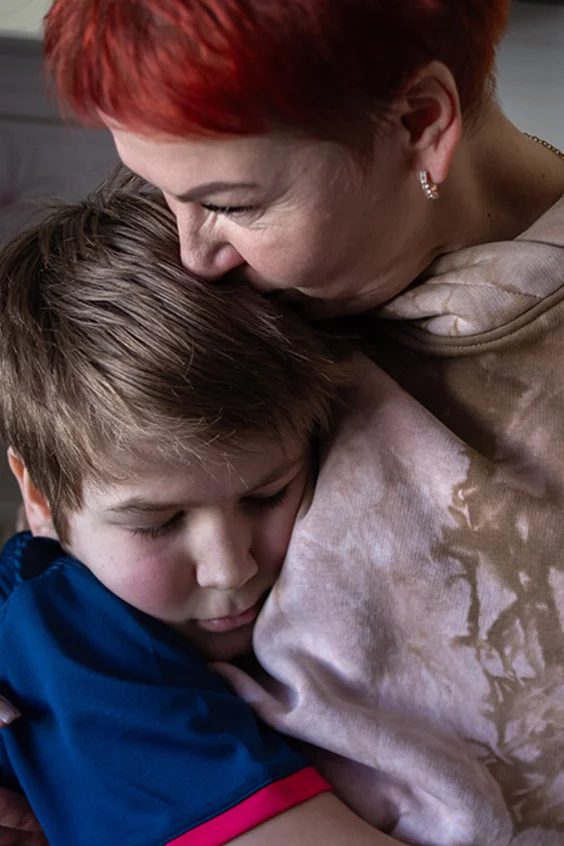 Ein Junge und seine Mutter liegen sich eng umschlungen in den Armen.