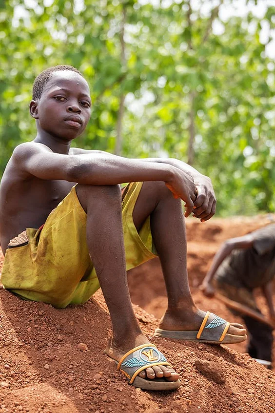 Am 12. März 2025 sitzt der 12-jährige Jean [NAME GEÄNDERT] auf einem Sandhaufen in der Kiesgrube, in der er in Couffo, Benin, arbeitet.
