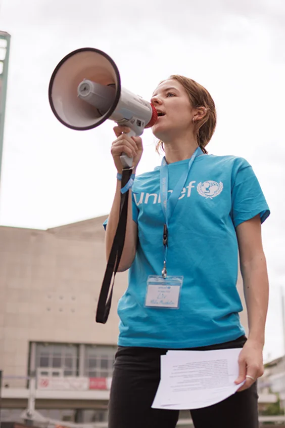 Mädchen trägt ein UNICEF T-Shirt und spricht in ein Megafon 
