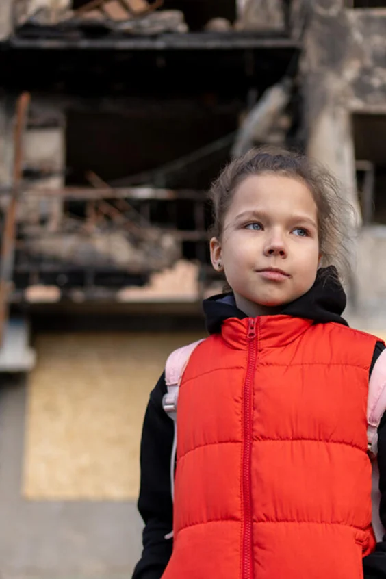 Ein Mädchen steht vor einem zerbombten Wohnhaus