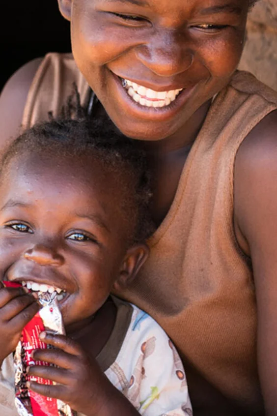 Edna Maunde, 20 anni, sorride mentre sua figlia Christina Cosmas, di 2 anni e 4 mesi, mangia alimenti terapeutici pronti all’uso (RUTF) nella loro casa nel villaggio di Mavila (Zomba, Malawi meridionale).